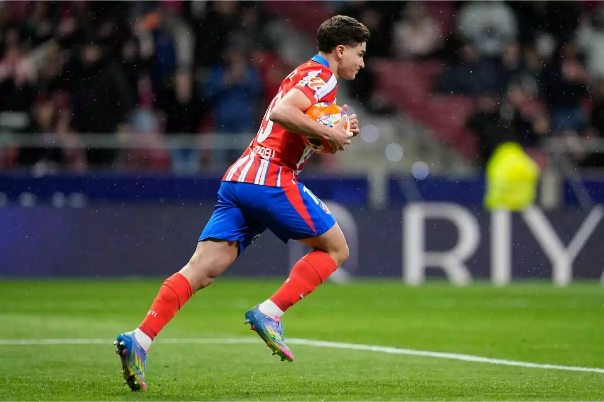 Jugador de fútbol corriendo en el campo con el balón en las manos durante un partido.